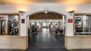 Une salle de sport dotée d’une large entrée, de divers équipements d’exercice et d’un panneau indiquant une capacité maximale de 75 personnes.
