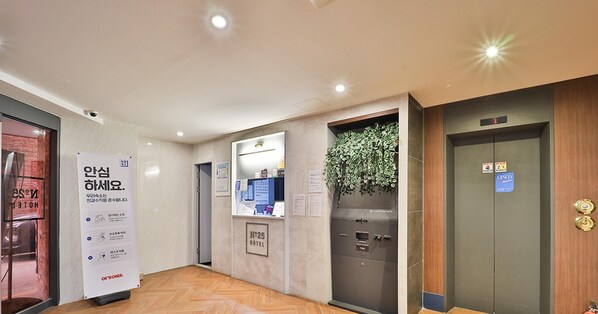 A hotel lobby with a reception desk, a wall-mounted plant, and an elevator. - number25hotel suyu (Seoul)