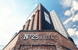 Un cartel de hotel con la inscripción 'N°25 HOTEL' sobre un muro de ladrillo.
