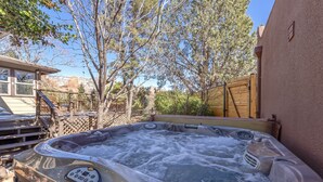A hot tub with a control panel, surrounded by a wooden deck and trees.