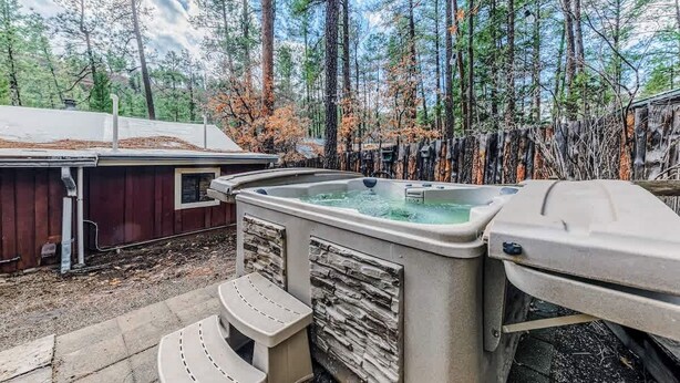 A hot tub in a wooded area with a wooden deck and a shed in the background.