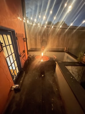 A courtyard with a decorative fire pit, a blue door, and string lights.
