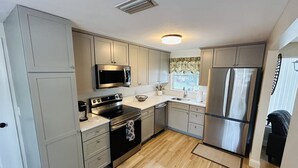 Una cocina moderna con armarios grises, electrodomésticos de acero inoxidable y piso de madera.