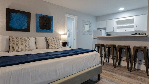A modern bedroom with a large bed, a nightstand, and a desk with stools. - Montrose Svelte Studio! Medical Center 47 (Houston)