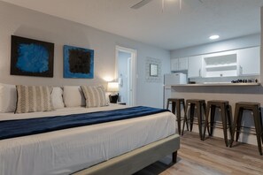 A modern bedroom with a large bed, a nightstand, and a desk with stools. - Montrose Svelte Studio! Medical Center 47 (Houston)