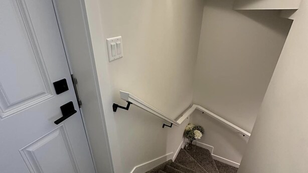 A staircase with carpeted steps, a handrail, and a light fixture above. - New, fresh, affordable, homey, 10 mins to the Edmonton Intl Airport. (Edmonton)