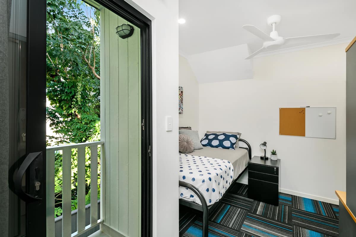Un dormitorio con cama, mesita de noche y ventilador de techo.