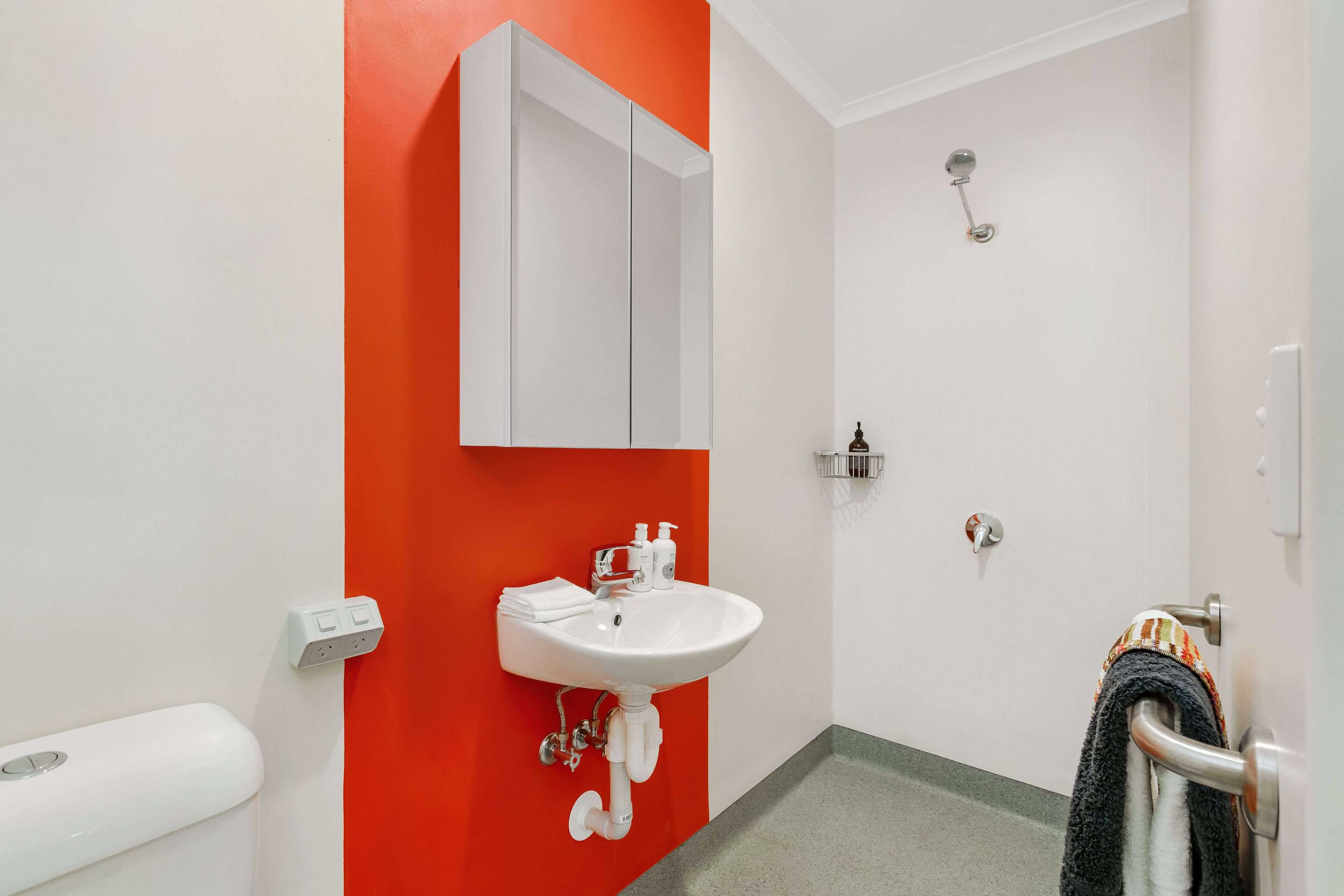 A bathroom with a white sink, a mirror, and a shower.