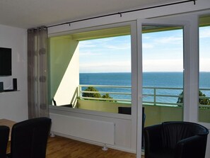 A room with a large window offering a view of the sea. - "meerbriese" Ferienpark Sierksdorf 2 Zimmer Apartment mit Meerblick - Ferienpark am Fahrenkroog (Sierksdorf)