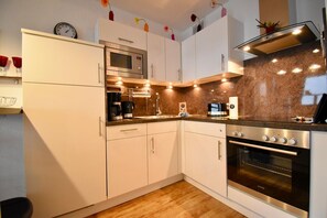 Eine moderne Küche mit weißen Schränken, einem Edelstahlbackofen, einer Mikrowelle und einer Kaffeemaschine.