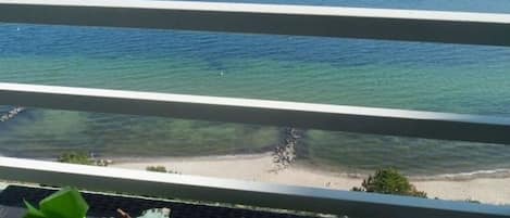 A balcony with a view of the ocean and a beach.
