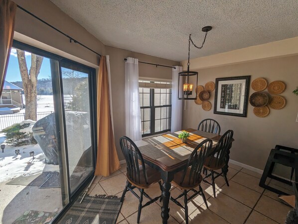 A dining area with a table set for four, a view of the outdoors, and decorative wall art.