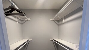 Ein begehbarer Kleiderschrank mit weißen Regaleinheiten und Holzboden.