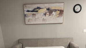 Ein Schlafzimmer mit Bett, Kopfteil, Wanduhr und einem Gemälde.