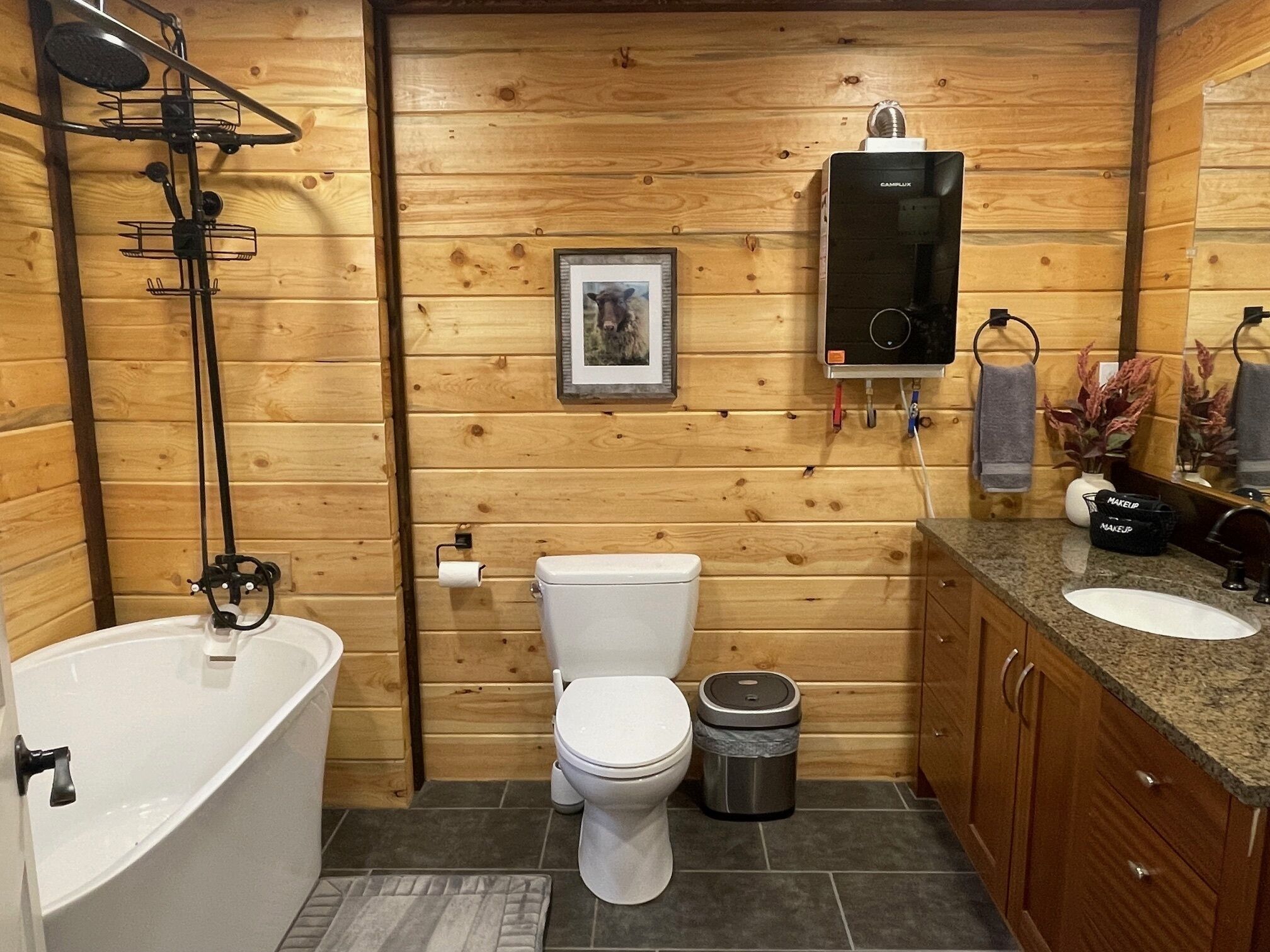 Une salle de bain aux murs lambrissés, équipée d’une baignoire, de toilettes, d’un meuble-lavabo et d’un radiateur.