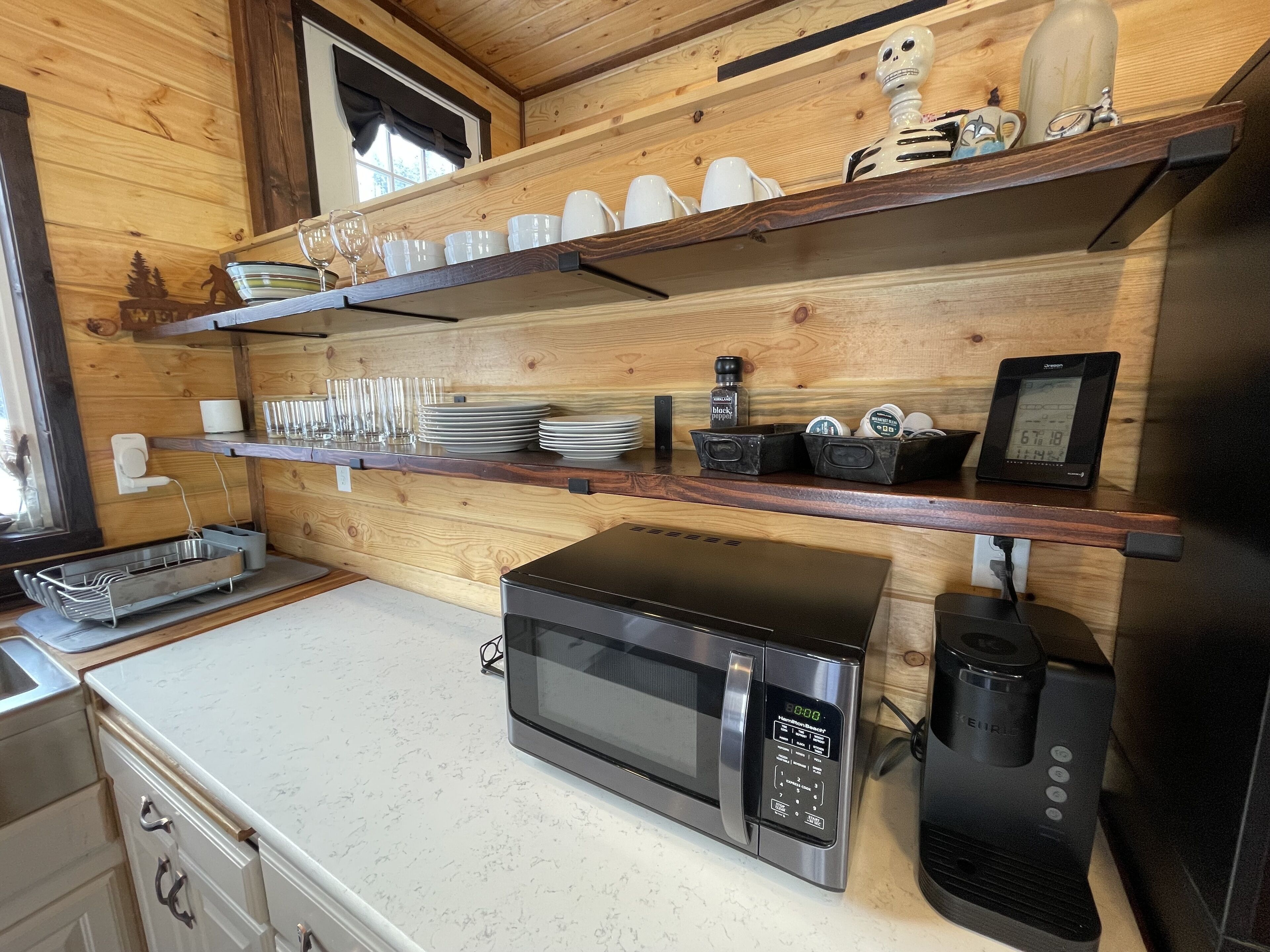 Eine Küche mit Holzböden, einer Mikrowelle, einer Kaffeemaschine und einer digitalen Uhr.