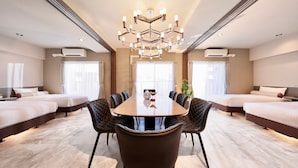 A hotel room with a large dining table, four upholstered chairs, two beds, and a chandelier. - Doutonboricrystalhotel3 (Osaka)