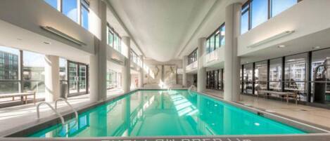 Una piscina interior moderna con paredes de vidrio transparente y un diseño espacioso.
