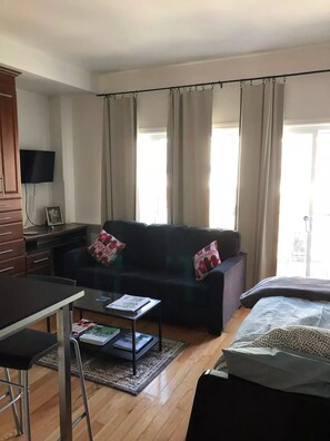 Una sala de estar con un sofá, una mesa de centro, un televisor y una cama.