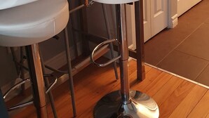 Een keuken met een bar, voorzien van een lange aanrecht en twee barkrukken.