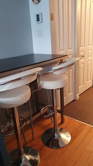Une cuisine dotée d’un coin bar comprenant un long comptoir et deux tabourets de bar.