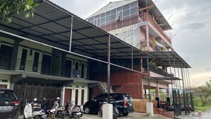 A multi-story building with a covered parking area, several parked vehicles, and a visible balcony. - OYO 93414 Wisma Ratu Syariah Near SMP Negeri 2 Watang Pulu (Watang Pulu)