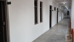 Un pasillo largo y estrecho con paredes blancas y puertas numeradas, que conduce a habitaciones individuales.