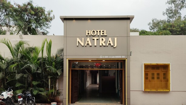 Exterior del Hotel Natraj con fachada moderna, entrada visible y un número de contacto sobre la puerta.