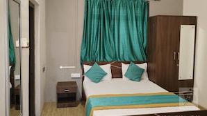 Un dormitorio con cama, mesita de noche, armario y cortina.