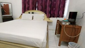 Une chambre d’hôtel équipée d’un lit, d’un bureau, d’une chaise, d’une télévision et d’une poubelle.