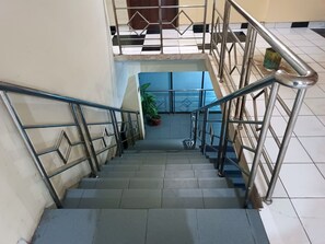 A staircase with metal railings and a potted plant at the bottom. - Hotel O Pondok Kula Rumbih Syariah (Aluhaluh)