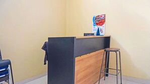 Un comptoir d’accueil avec un revêtement noir et en bois, une chaise bleue et un tabouret.
