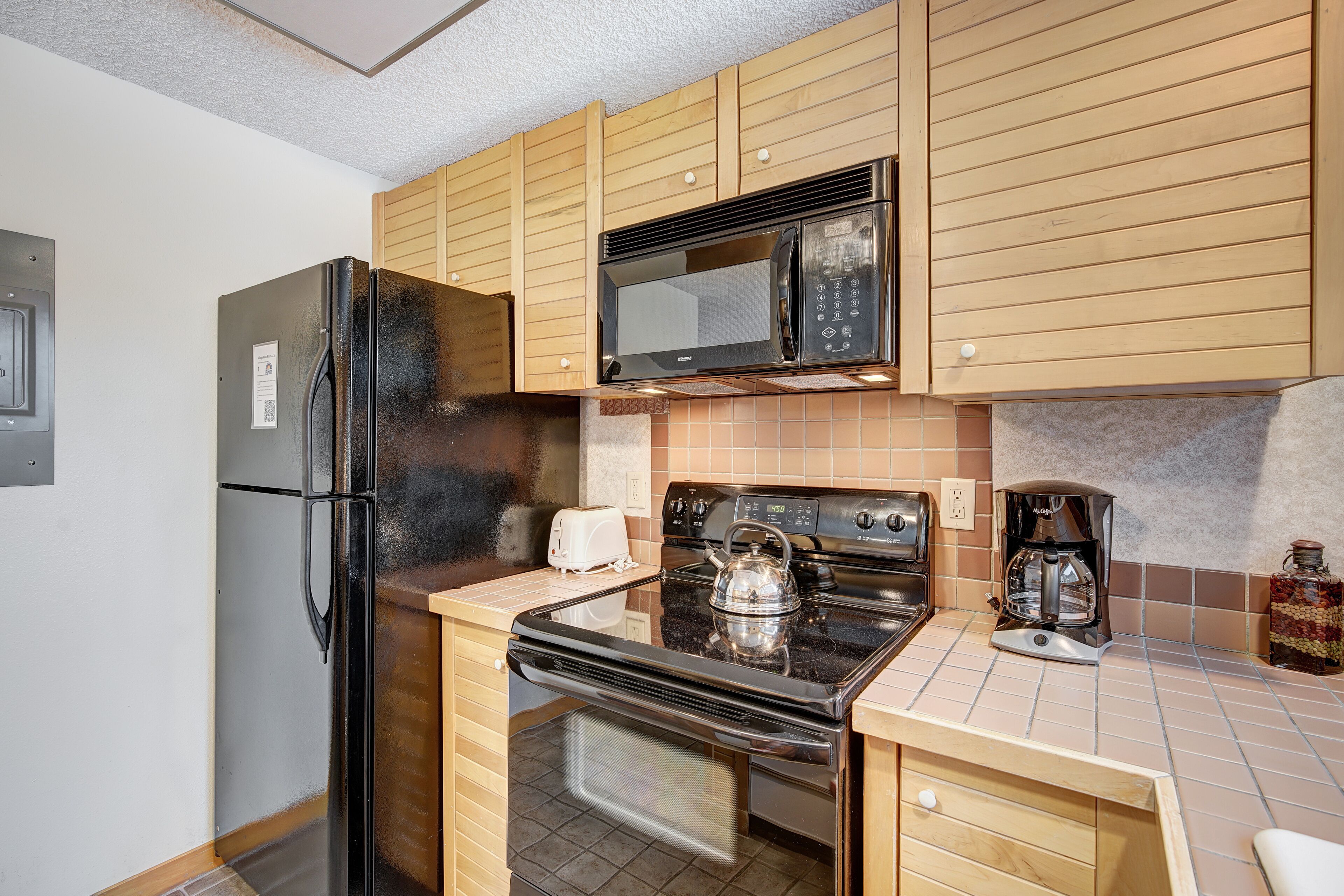 A compact kitchen with a refrigerator, microwave, stove, and toaster.