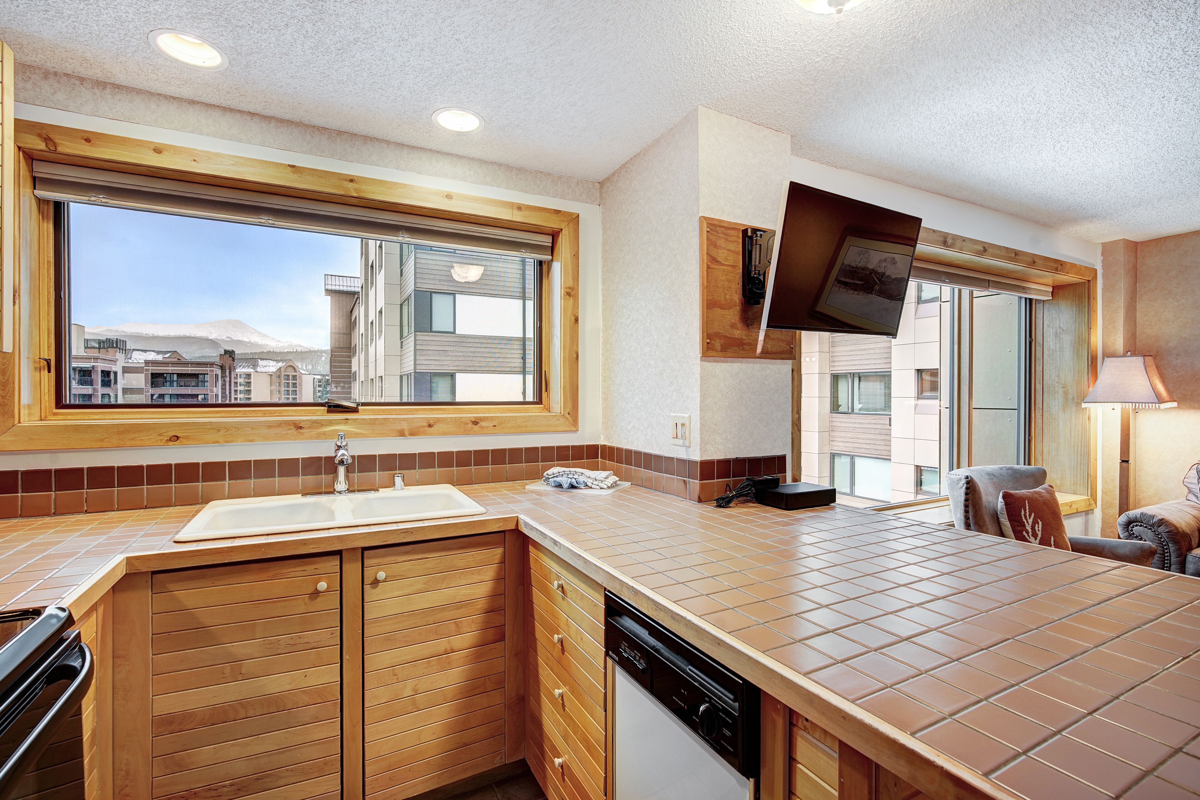 A modern kitchen with wooden cabinets, a large window, and a built-in oven.