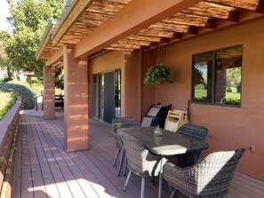 An outdoor patio with a table and chairs, a hanging plant, and a view of the garden. - New Listing! Epic Redrock Views, Golf Course, Sedona's Best Neighborhood! (Sedona)