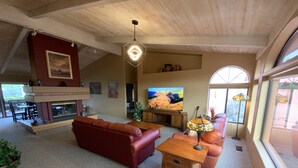 Ein geräumiges Wohnzimmer mit Kamin, Ledersofas, einem Holztisch und einem großen Fernseher.