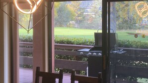 Eine Terrasse mit Grill und Blick auf einen Golfplatz.