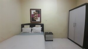 Un dormitorio con cama, mesita de noche, armario y un cuadro en la pared.