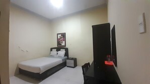 Un dormitorio pequeño y ordenado con cama, mesita de noche y escritorio con espejo.
