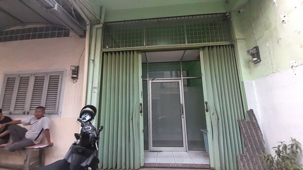 Entrada de un edificio con una puerta verde y una motocicleta estacionada afuera.