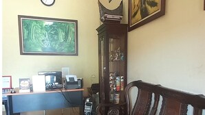 Una habitación con sofá, escritorio con computadora, reloj y obras de arte enmarcadas en la pared.