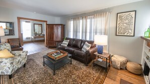 A living room with a brown leather sofa, a patterned armchair, a coffee table, and a side table with a lamp.