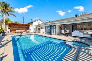 Relax by the pool surrounded by a patio area with comfortable seating and a living space with a view.