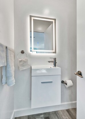 Bathroom features a sleek vanity, mirror, and towel rack.