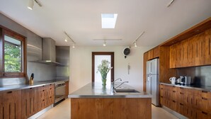 A modern kitchen with stainless steel appliances, wooden cabinets, and a central island. - Villa Nusantara  (Denpasar)