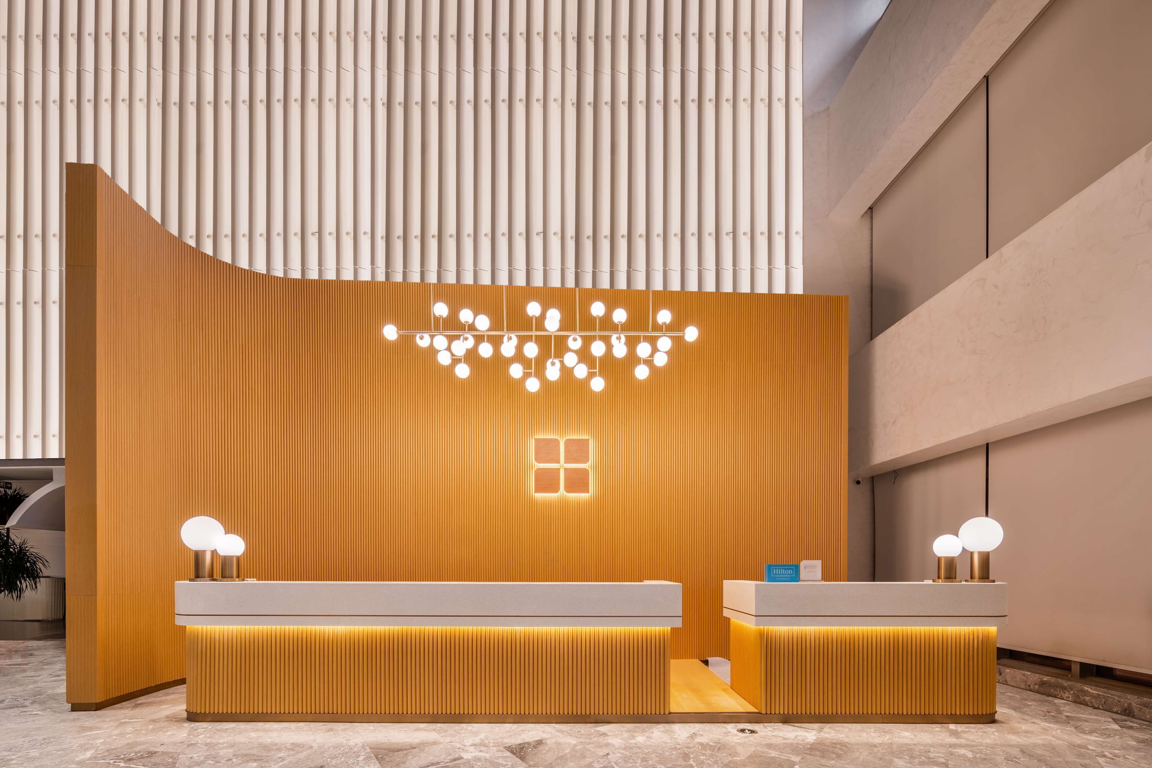 Uma receção moderna com acabamento em madeira, duas globos iluminados e design minimalista.