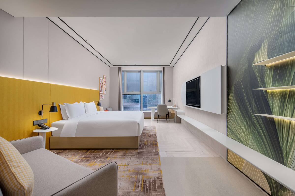 Une chambre d’hôtel moderne, dotée d’un grand lit, d’un bureau et d’une télévision.