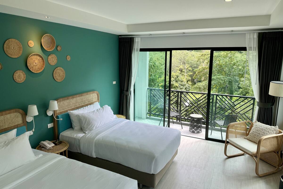 A hotel room with two beds, a balcony with a table and chairs, and decorative woven wall art.