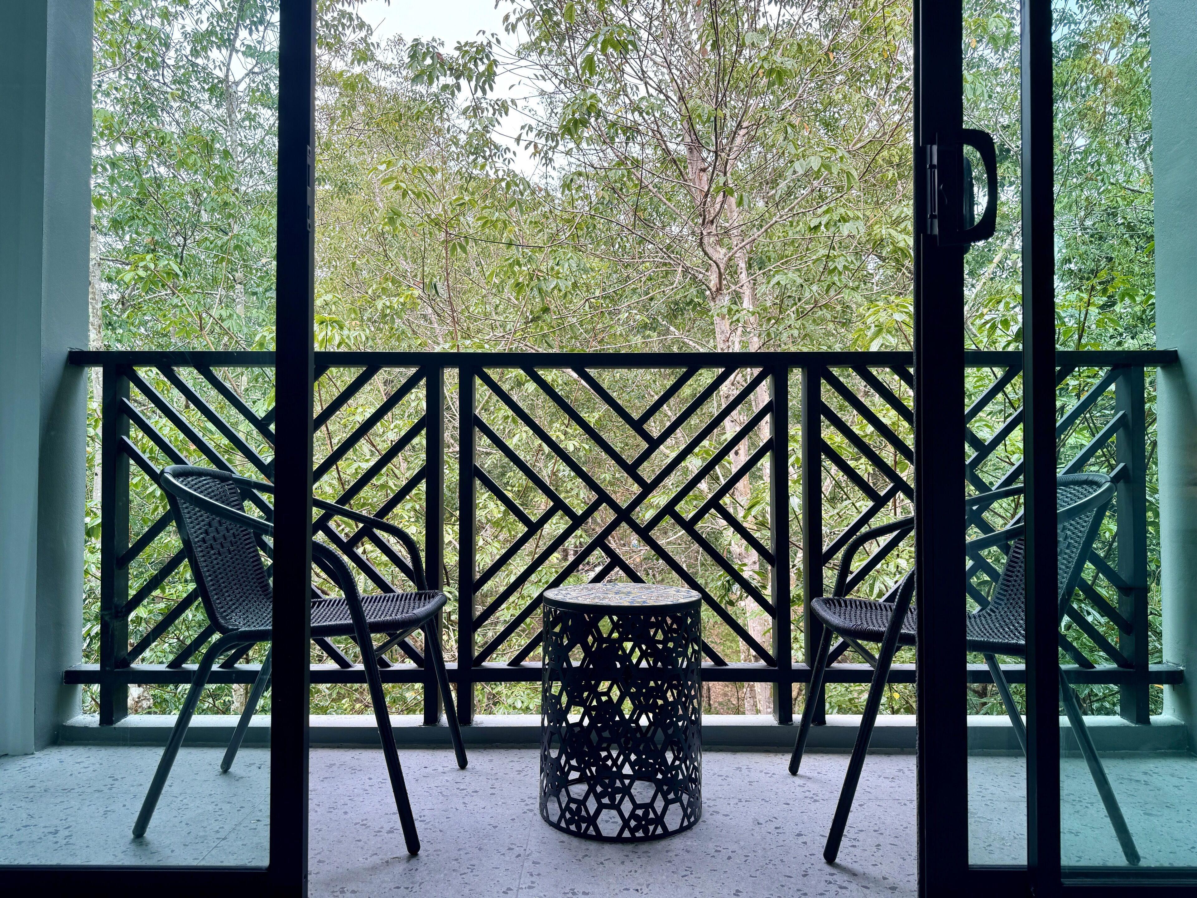 A balcony with a wrought iron railing, two chairs, and a small round table.