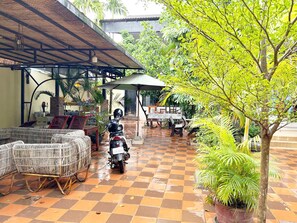 Un espacio al aire libre techado con piso a cuadros, una motocicleta y plantas en macetas.